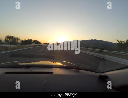 La guida al tramonto presso l'autostrada vista dall'interno della vettura. Concetto di viaggio Foto Stock