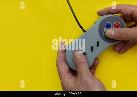 L'uomo la riproduzione del video gioco con il controller su sfondo giallo Foto Stock