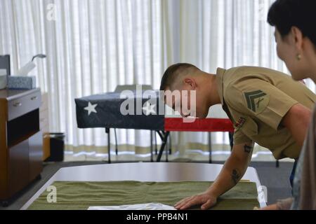 Stati Uniti Marine Corps Cpl. Nathaniel Walters sorge dai resti del suo prozio, U.S. Pfc dell'esercito. Joe S. Elmore, prima del trasporto durante una catena di custodia evento al senatore Daniel K. Inouye centro di eccellenza su base comune Harbor-Hickam perla, Hawaii, 14 agosto 2018. Walters ha visitato la difesa POW/mia agenzia di contabilità (DPAA) come parte dei suoi doveri come NEGLI STATI UNITI Militari di scorta speciale per la sua grande di suo zio rimane in rotta verso il luogo del riposo finale in un cimitero vicino la famiglia della casa di Kentucky. Foto Stock