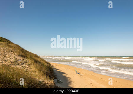 Solitaria sedia verde sulla sabbiosa e ventoso spiagge del mare adriatico Foto Stock