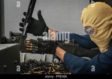 Oceano Pacifico (Agosto 12, 2018) Aviation Ordnanceman 2a classe Erwin Louis, da Dededo, Guam, ri-carica un M240B mitragliatrice sul fiocco di assalto anfibio nave USS Bonhomme Richard (LHD 6) durante un live fire esercizio. Bonhomme Richard è attualmente in corso negli Stati Uniti La terza area della flotta di operazioni. Foto Stock