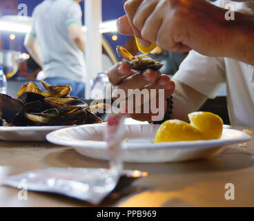 Cozze ripiene e uomo squeeze limone. midye dolma in lingua turca Foto Stock