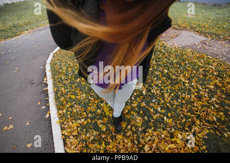 Donna gambe in stivali e blu jeas contro uno sfondo giallo Foglie di autunno. Vista dall'alto. Stagionale e concetto di moda. Foto Stock