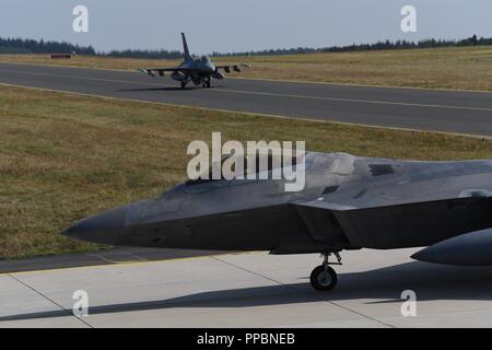 Un U.S. Air Force F-22 Raptor dalla 95th Fighter Squadron, 325Fighter Wing, a Tyndall Air Force Base Fla., e un U.S. Air Force F-16 Fighting Falcon assegnato alla 480th Fighter Squadron, Spangdahlem Air Base, Germania, taxi verso il basso la Flightline a Spangdahlem AB, il 29 agosto 2018. Il velivolo addestrati con altri partner della NATO durante il F-22 Flying Training distribuzione. Foto Stock