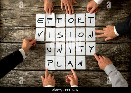 Otto business partner detiene carte bianche con lettere su di loro formando elementi più importanti del business di successo - sforzo, visione, unità e pl Foto Stock
