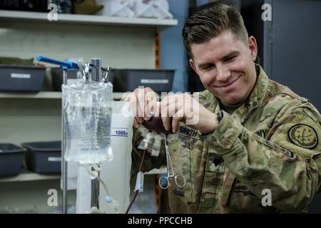 Stati Uniti Army Spc. Andrew Smith, un combattimento Medic specialista, spremere un sacca di sangue per aumentare il sangue durante una trasfusione di sangue di classe al raccordo 3 di truppa di clinica medica a Baghdad, Iraq, Agosto 17, 2018. Combined Joint Task Force - Funzionamento inerenti risolvere mira a consentire ed equipaggiare le forze locali di prendere ISIS sulla testa mentre sfruttando la nazione di coalizione airpower a sconfiggere ISIS in Iraq e la Siria. Foto Stock