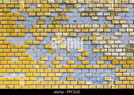 Vecchio weathered dipinte di un giallo la parete in mattoni con elementi mancanti. Età compresa tra superficie del blocco con parti cadere. Calcestruzzo outdor grunge background urbano Foto Stock