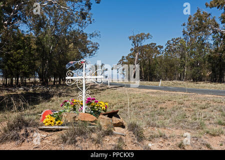 Memoriale sul ciglio della strada per la vittima di incidente con un elaborato una Croce Cristiana e fiori. Rural NSW Australia. Foto Stock