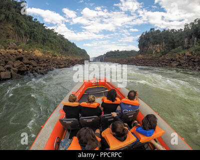 I turisti con giubbotti salvagente seduto in zattera gonfiabile durante il tour di Iguazu Falls National Park, Parana, Brasile Foto Stock