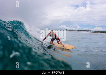 Grandi nuvole su maschio surfer wave riding, maschio, Maldive Foto Stock