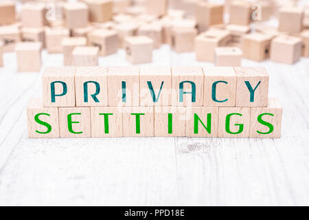 Le parole le impostazioni sulla privacy formata da blocchi di legno su un tavolo bianco Foto Stock