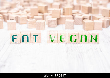 Le parole di mangiare Vegan formata da blocchi di legno su un tavolo bianco Foto Stock