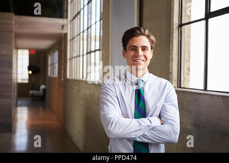 Giovane imprenditore bianco sta sorridendo con le braccia incrociate Foto Stock