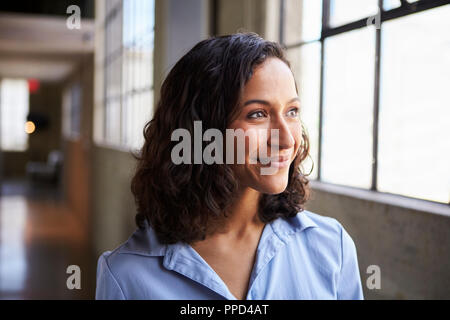 Sorridente giovane razza mista imprenditrice guardando lontano Foto Stock