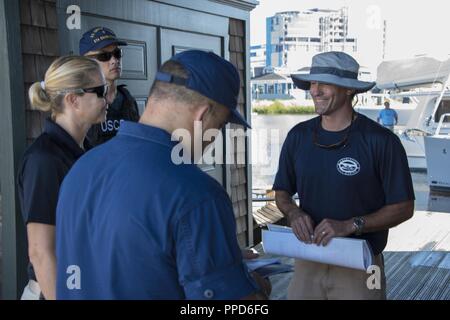 Lt. La Cmdr. Kerry duca, un indagando officer presso Coast Guard Settore Charleston, Bridget Wyant, una guardia costiera agente speciale, e Sottufficiali terza classe Casy Strawn, una di boatswain mate alla Stazione della Guardia Costiera Charleston, discutere illegale e charter nautica con sicurezza un Charleston City Marina membro dello staff Agosto 30, 2018 a Charleston, Carolina del Sud. Il duca, Wyant e Strawn camminato i docks di vari porti in tutta Charleston per educare il pubblico su illecita charter nautica e sicurezza. Foto Stock