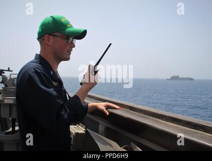 Stretto di Hormuz (sett. 4, 2018) Il tenente j.g. Rob Hickey sorge guarda come ufficiale di coperta come guidato-missile destroyer USS Il Sullivans (DDG 68) conduce una routine transito attraverso lo Stretto di Hormuz al fianco di carichi secchi e munizioni nave USNS Richard E. Byrd (T-AKE 4). Il Sullivans è distribuito negli Stati Uniti Quinta Flotta area di operazioni a sostegno di operazioni navali per garantire stabilità marittimo e la sicurezza nella regione centrale di collegamento del Mediterraneo e del Pacifico attraverso l'Oceano Indiano occidentale e tre strategici punti di strozzatura. Foto Stock