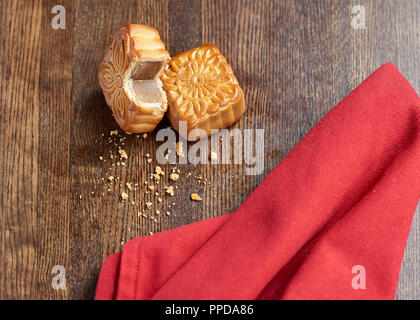 Mooncake tagliato su sfondo di legno con sfondo rosso Foto Stock