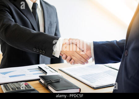 Due uomini di business partner si stringono la mano durante una riunione per trattare completare a firmare un accordo contrattuale e diventare il successo in ufficio Foto Stock