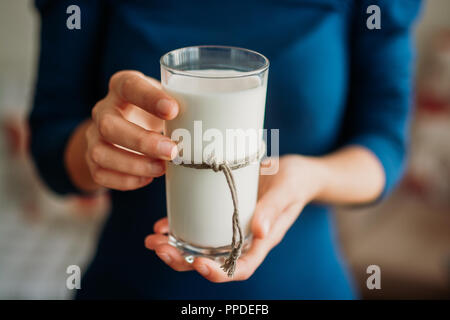 Giovane donna mani tenendo un bicchiere di latte. Foto Stock