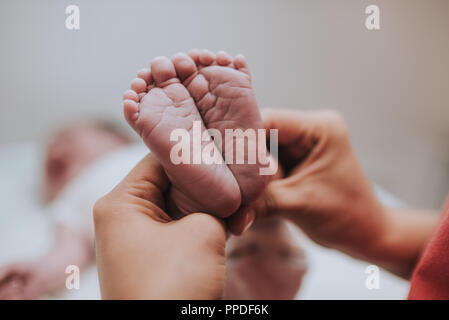 Madre tenendo in mano i piedi del neonato. Foto Stock