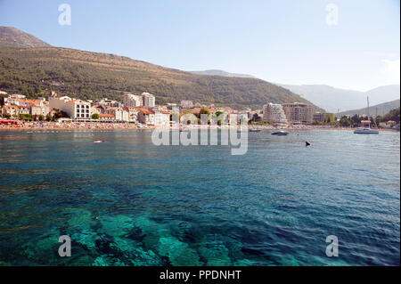 Vista sulla spiaggia del villaggio idilliaco, Petrovac in Montenegro, l'Europa. Cielo blu chiaro e acque blu turchese. Foto Stock