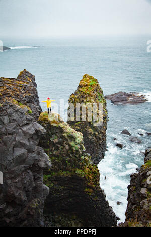 Paesaggio islandese, persona in giallo Giacca pioggia. Amasing rock, Islanda. Foto Stock