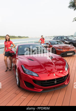 Ferrari Portofino, Aston Martin Vantage e Bentayga V8 automobili di lusso sul display con attraenti modelli al Gran Premio di F1 di Marina Bay Singapore Asia Foto Stock