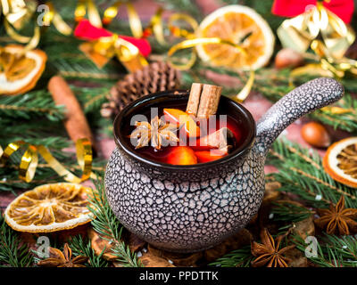 Natale vin brulé con cannella, arancione e anice stellato in un vaso in ceramica con decorazioni d'inverno. Foto Stock