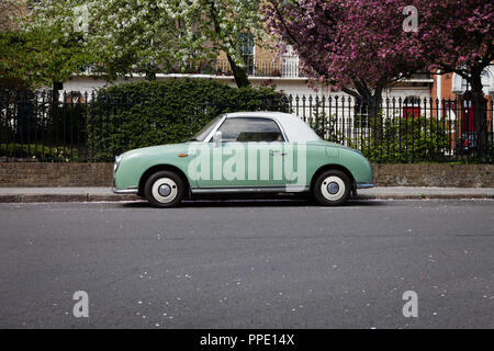 Nissan Figaro parcheggiato di fronte di alberi in fiore, Islington, Londra. Foto Stock