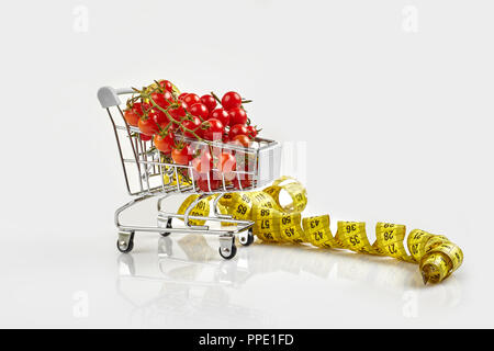 Mini carrello pieno con pomodori ciliegia su sfondo bianco. Spazio di copia Foto Stock