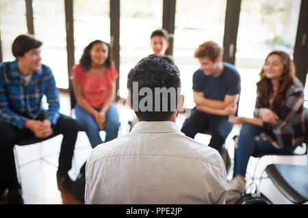 Vista posteriore del Tutor maschio leader di gruppo di discussione tra gli alunni delle scuole Foto Stock