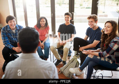 Vista posteriore del Tutor maschio leader di gruppo di discussione tra gli alunni delle scuole Foto Stock