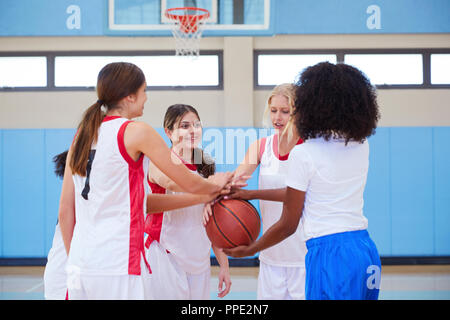 Femmina di alta scuola i giocatori di basket di unire le vostre mani durante il Team parla con pullman Foto Stock