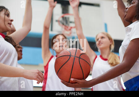 Femmina di alta scuola i giocatori di basket di unire le vostre mani durante il Team parla con pullman Foto Stock
