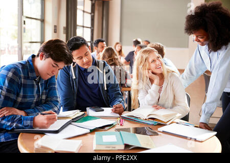 Un gruppo di studenti di scuola superiore con insegnante femmina lavorare alla scrivania Foto Stock