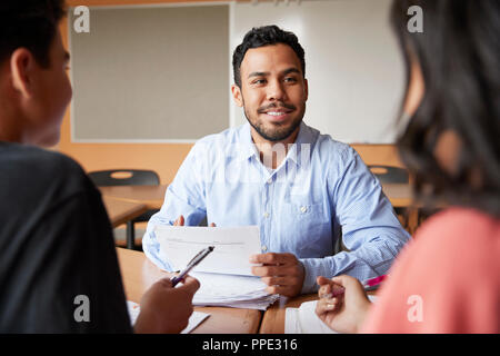 Maschio della High School Tutor con due studenti al banco in seminario Foto Stock