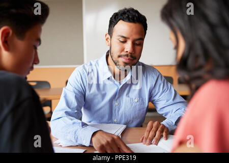 Maschio della High School Tutor con due studenti al banco in seminario Foto Stock