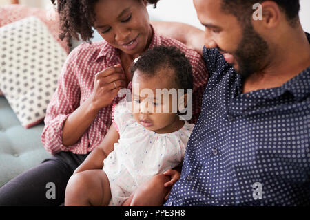 Famiglia con la nostra bambina seduti sul divano di casa insieme Foto Stock