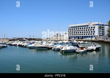 Piccole barche a motore ormeggiata in porto turistico con un waterfront hotel verso la parte posteriore, Faro, Algarve, Portogallo, dell'Europa. Foto Stock