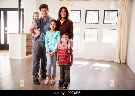 Ritratto di famiglia felice con il bambino in piedi nella sala vuota della nuova casa Foto Stock