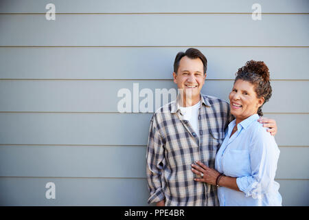 Ritratto di coppia Senior in piedi fuori clapboard grigie House Foto Stock