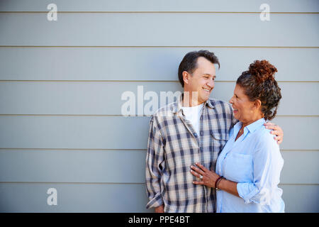 Coppia senior in piedi fuori clapboard grigie House Foto Stock