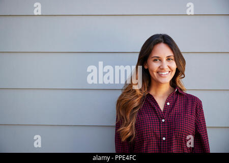 Ritratto di giovane donna in piedi fuori clapboard grigie House Foto Stock