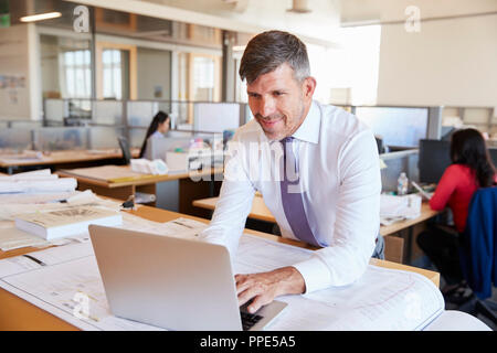 Di mezza età architetto maschio utilizzando computer portatile in ufficio open space Foto Stock