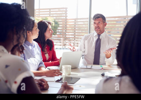 Manager maschio si siede a parlare con i colleghi in una sala riunioni Foto Stock