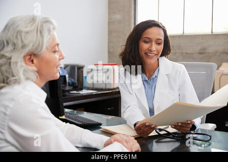 Donna sorridente medico in consultazione con paziente senior Foto Stock
