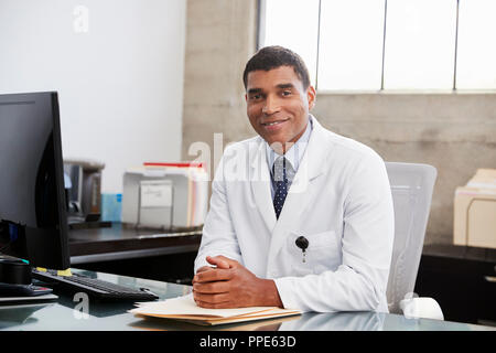 Gara di misto medico maschio alla scrivania, ritratto Foto Stock