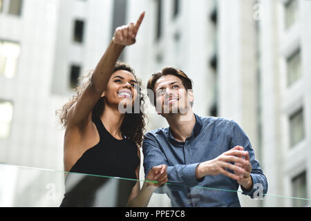 Felice coppia internazionale hanno una conversazione in città. Razza mista donna e uomo caucasico. Foto Stock
