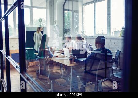 Lavorando duro per vincere. Imprenditrice condurre una presentazione con lavagna a fogli mobili mentre si lavora in ufficio creativo. Foto Stock