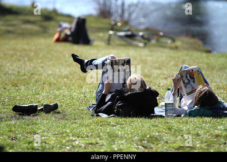 Prendere il sole a temperature primaverile presso il fiume Eisbach nel Giardino Inglese. Foto Stock